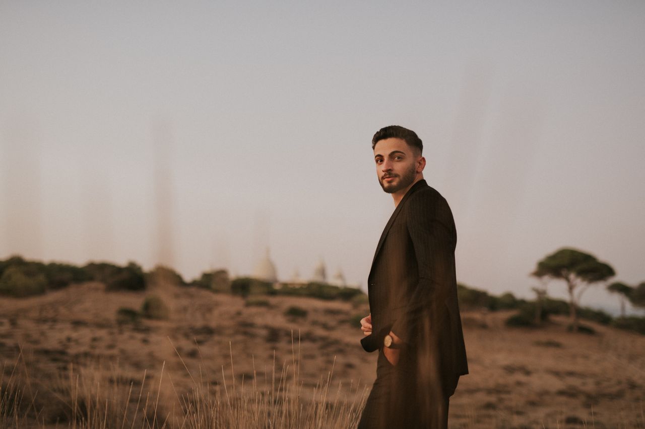 A man in a suit posing outdoors during sunset, capturing an elegant and serene moment.